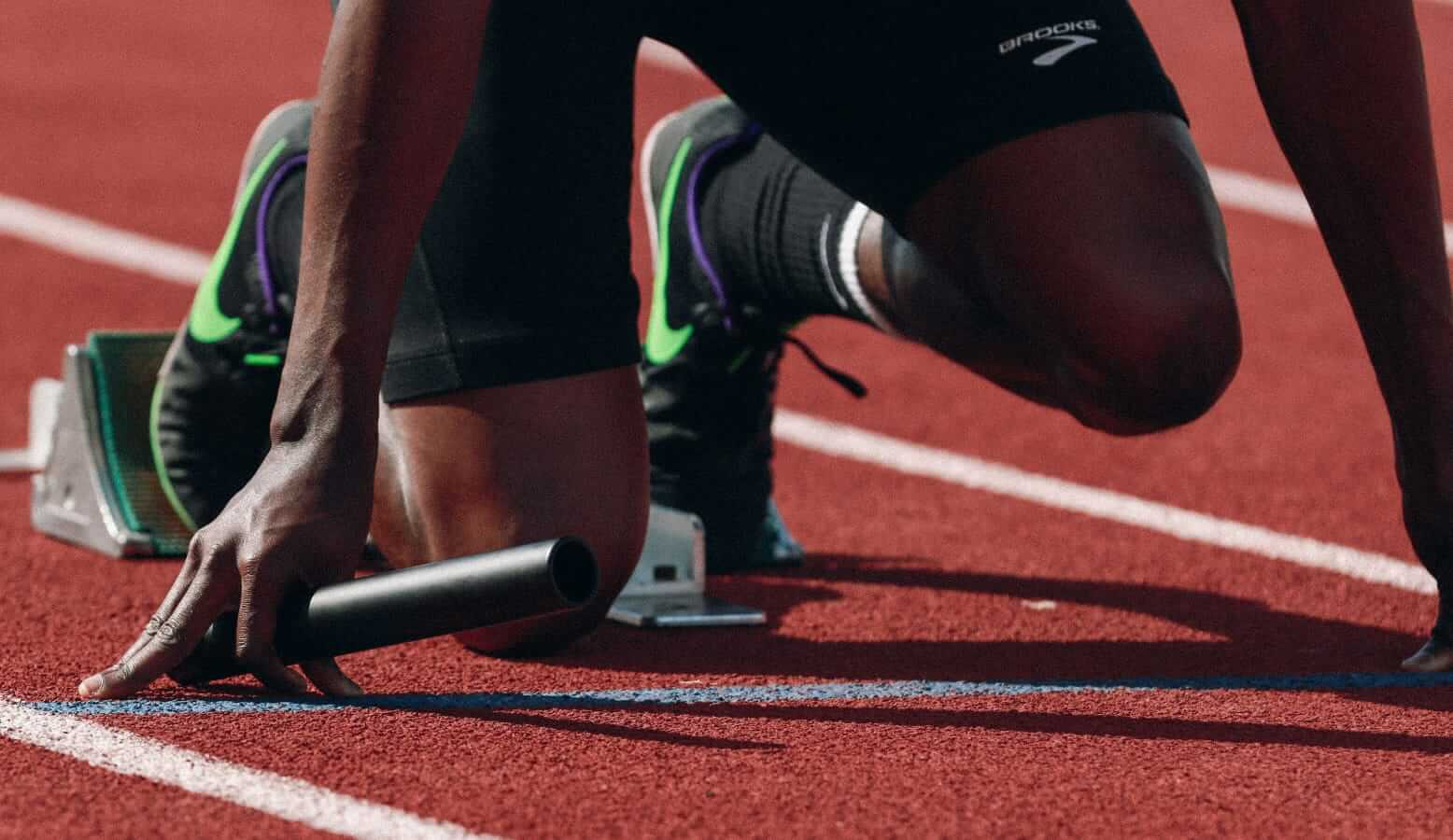 Close up of a man at the starting blocks for a track relay.